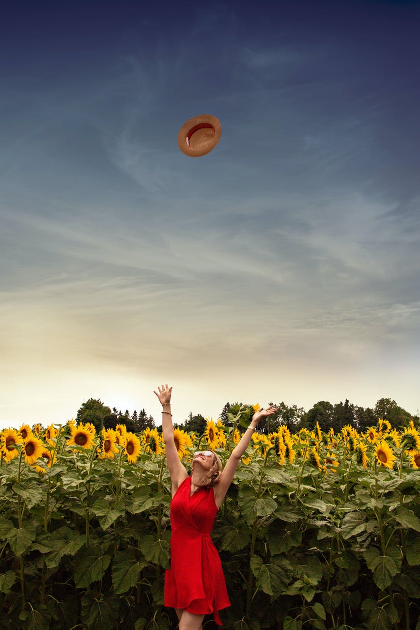 photo of woman throwing her straw hat upwards